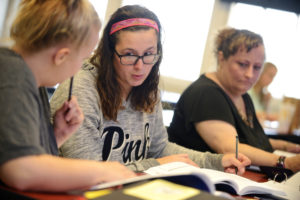 Students working together on coursework; two of them look dubious.